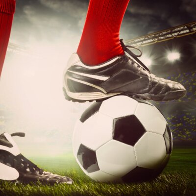 De benen van de voetballer op een bal