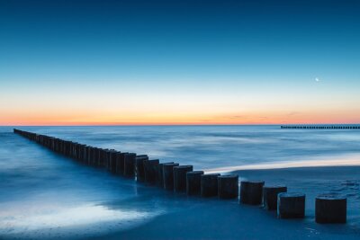 De zee en golfbreker na zonsondergang