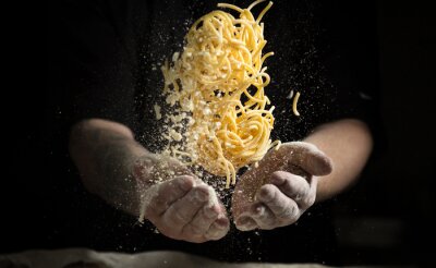 Fotobehang dichtbije hand maken pasta toss op een zwarte achtergrond voor het koken van de schotel