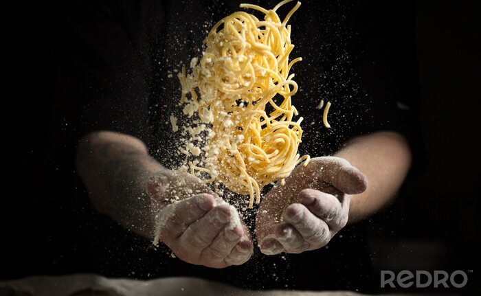 Fotobehang dichtbije hand maken pasta toss op een zwarte achtergrond voor het koken van de schotel