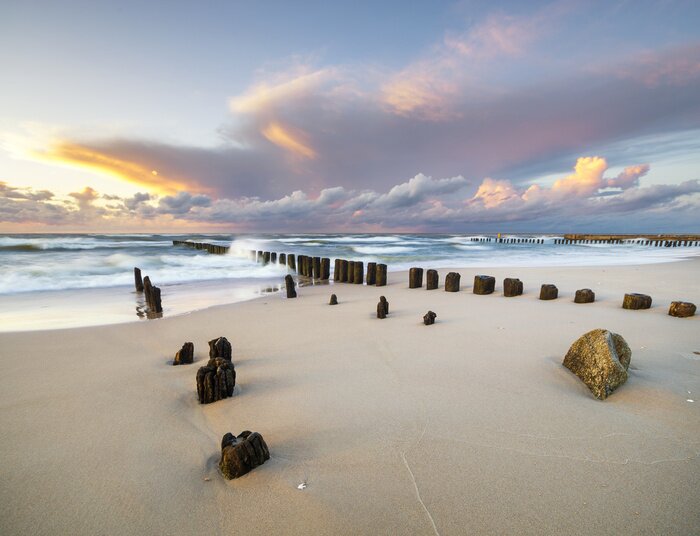 Fotobehang Dynamische landschap van zee, de golven breken op de golfbreker, zonsondergang op de zee strand