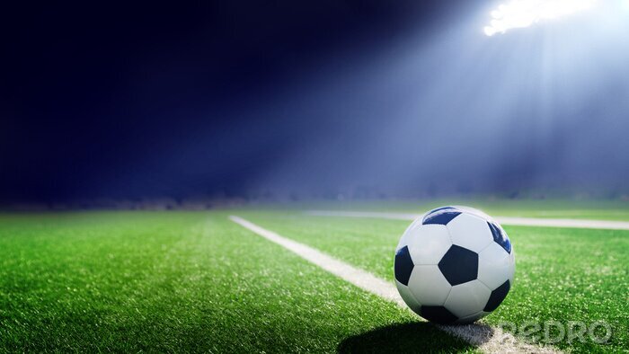 Fotobehang Een bal die op de grasmat ligt, verlicht door een schijnwerper