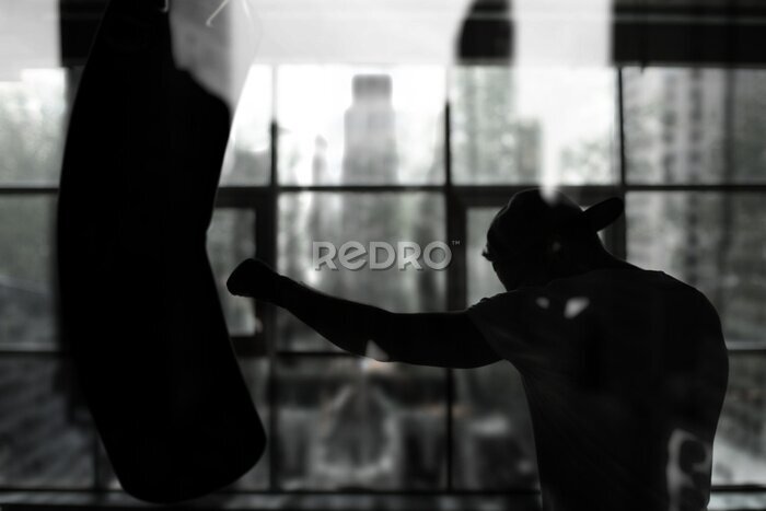 Fotobehang Een bokser die op een bokszak slaat