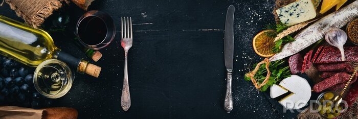 Fotobehang Een fles wijn, kazen en traditionele worsten op een houten achtergrond. Brie, blauwe kaas, gorgonzola, fuete, salami. Vrije ruimte voor tekst. Bovenaanzicht.