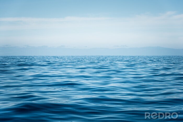 Fotobehang Een kalme oceaan tegen een blauwe lucht
