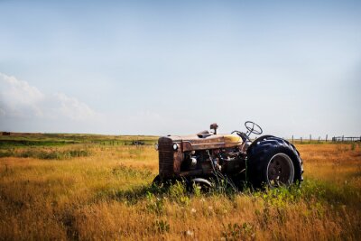 Fotobehang Een oude uitstekende rode geroeste tractorzitting in een geschermd weiland in een landbouw landelijk landschap van het de zomerplatteland