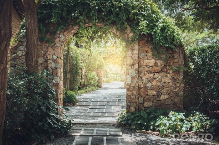 Fotobehang Een stenen gang die naar de tuin leidt