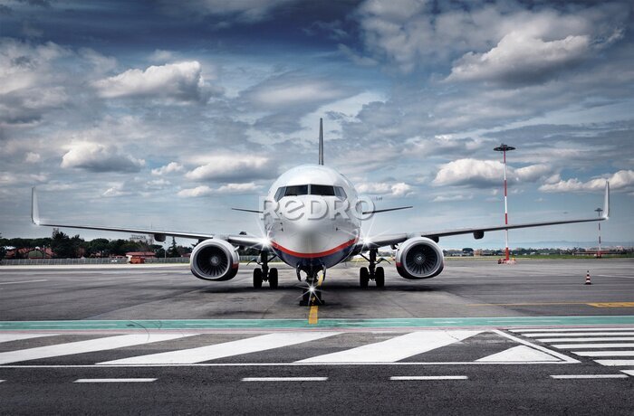 Fotobehang Een vliegtuig op de luchthaven tegen een bewolkte lucht