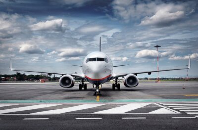 Fotobehang Een vliegtuig op de luchthaven tegen een bewolkte lucht