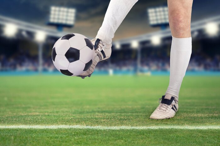 Fotobehang Een voetballer die de bal in het stadion schopt