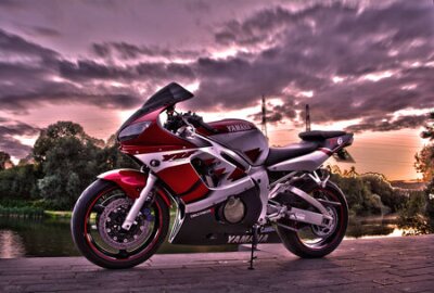 Fotobehang Een Yamaha-motorfiets tegen een achtergrond van groen en een bewolkte lucht