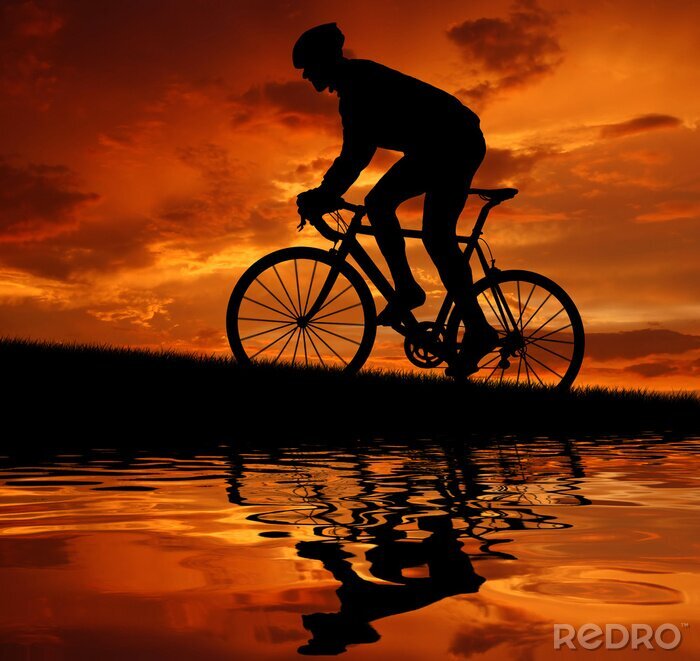 Fotobehang Fietser tegen de achtergrond van de ondergaande zon