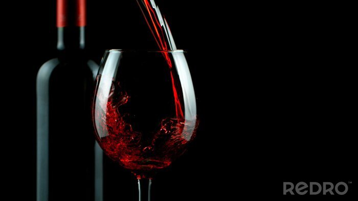 Fotobehang Fles en wijn in een glas op een zwarte achtergrond
