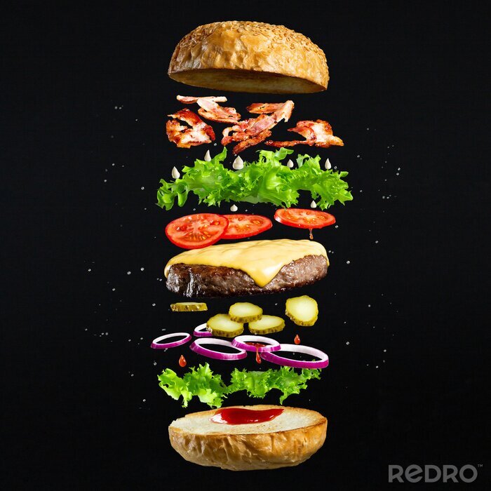 Fotobehang Floating burger isolated on black wooden background. Ingredients of a delicious burger with ground beef patty, lettuce, bacon, onions, tomatoes and cucumbers