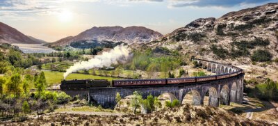 Fotobehang Glenfinnan Railway Viaduct in Schotland met de Jacobite stoomtrein tegen zonsondergang over lake