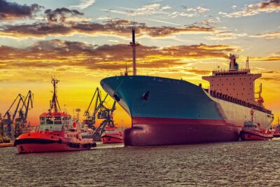 Fotobehang Groot schip met het escorteren van sleepboten vertrek uit de haven bij zonsondergang.