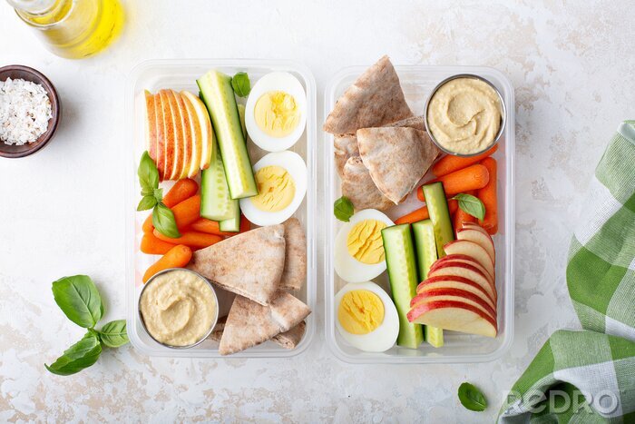 Fotobehang Healthy and nutricious lunch or snack boxes to go with hummus and pita, eggs and vegetables