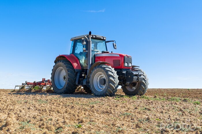 Fotobehang landbouw tractor op de voorgrond met blauwe hemel achtergrond.