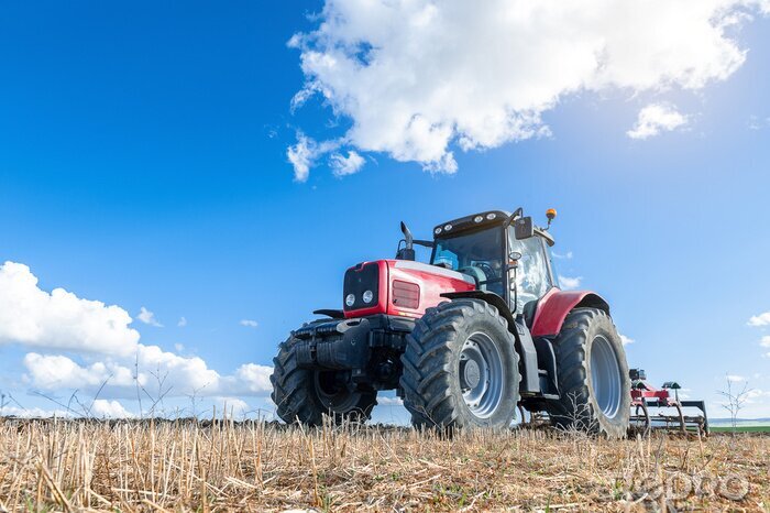 Fotobehang Landbouw tractor op de voorgrond met blauwe hemel achtergrond.