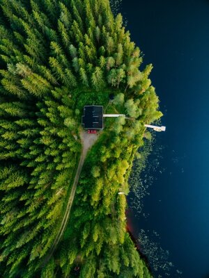 Luchtmening van houten plattelandshuisje in groen bos door het blauwe meer in de landelijke zomer Finland