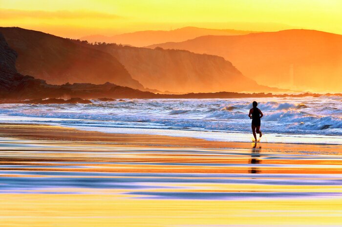 Fotobehang Man op het strand bij zonsondergang
