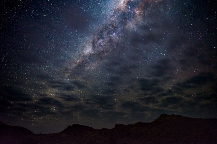 Fotobehang Melkwegboog, sterren in de lucht, de Namib-woestijn in Namibië, Afrika. Enkele schilderachtige wolken.