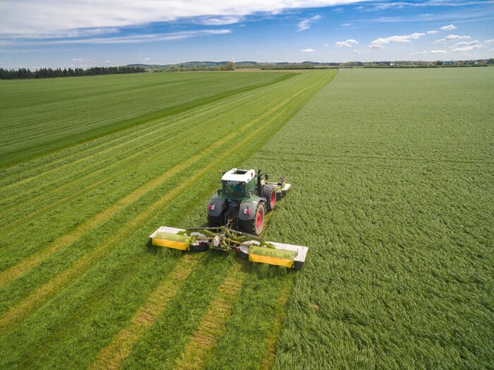 Fotobehang Moderne tractor die aan het landbouwgebied werkt - tractor die en op het landbouwgebied ploegen zaaien - luchtmening - hoge hoogste mening