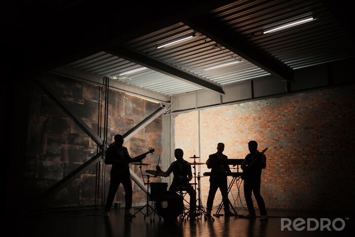 Fotobehang Muziekband en mode. Knappe jonge mannen in kostuums rock spelen en lied zingen. Bandsilhouetten met op een concert.