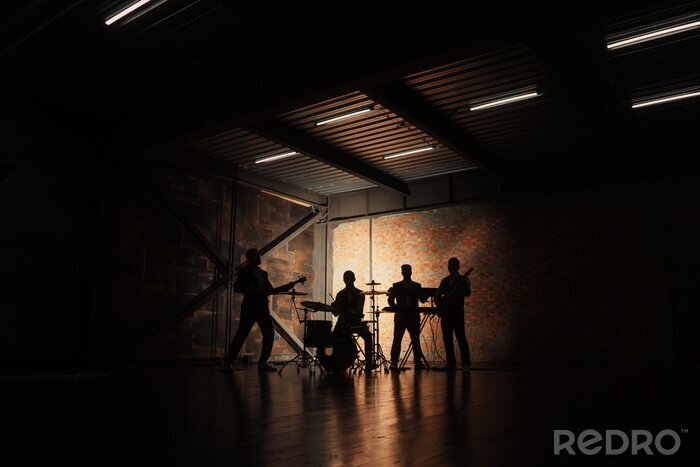 Fotobehang Muziekband en mode. Knappe jonge mannen in kostuums rock spelen en lied zingen. Bandsilhouetten met op een concert.