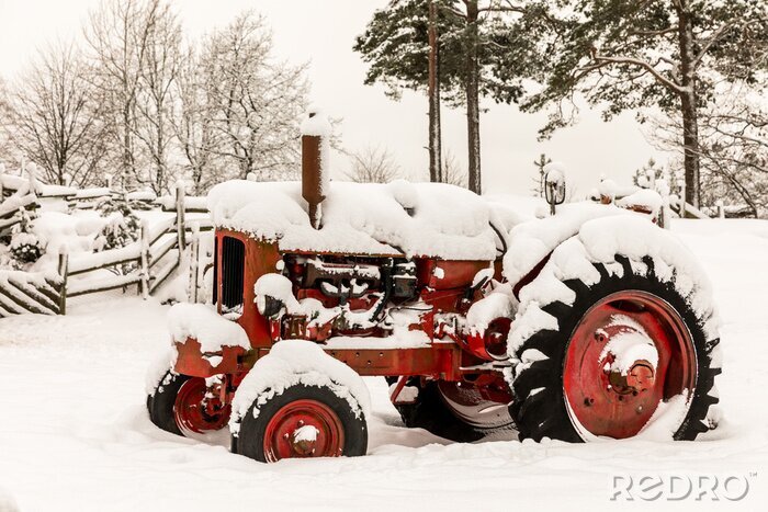 Fotobehang Oude rode tractor die in sneeuw wordt behandeld