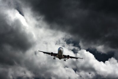 Fotobehang Passagiersvliegtuig tegen stormachtige hemel