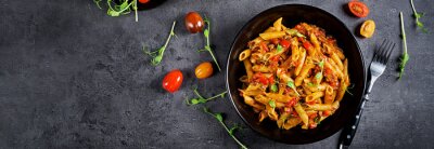 Fotobehang Penne pasta in tomato sauce with meat, tomatoes decorated with pea sprouts on a dark table. Top view. Banner