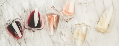 Plat van rode, rose en witte wijn in glazen en kurkentrekkers over grijze marmeren achtergrond, bovenaanzicht, brede samenstelling. Wijnbar, wijnmakerij, wijn degustatie concept