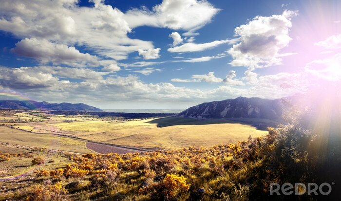 Fotobehang Puesta del sol paisaje. Los campos y sol. Cielo azul y nubes