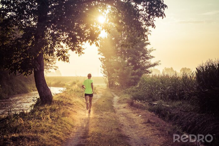 Fotobehang Ragazzo che corre all'alba su strada di Campagna in estate