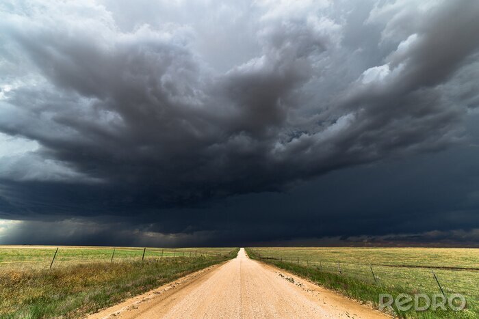 Fotobehang Regenwolken boven een veldweg