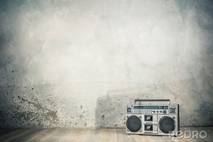 Fotobehang Retro outdated portable stereo boombox radio cassette recorder from 80s front concrete wall background with shadow. Vintage old style filtered photo