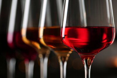 Row of glasses with different wines on blurred background, closeup