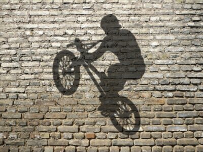 Fotobehang Schaduw van de fietser op de muur