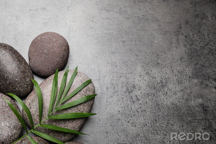 Fotobehang Spa stones and palm leaf on grey table, flat lay. Space for text