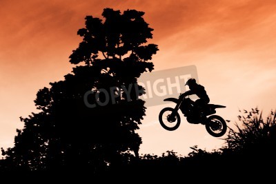 Fotobehang Status van silhouate motorcross springen over het oranje licht van de zonsondergang achtergrond.