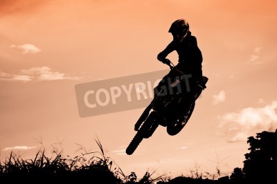 Fotobehang Status van silhouate motorcross springen over het oranje licht van de zonsondergang achtergrond.