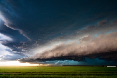 Fotobehang Stormwolken boven een groen veld
