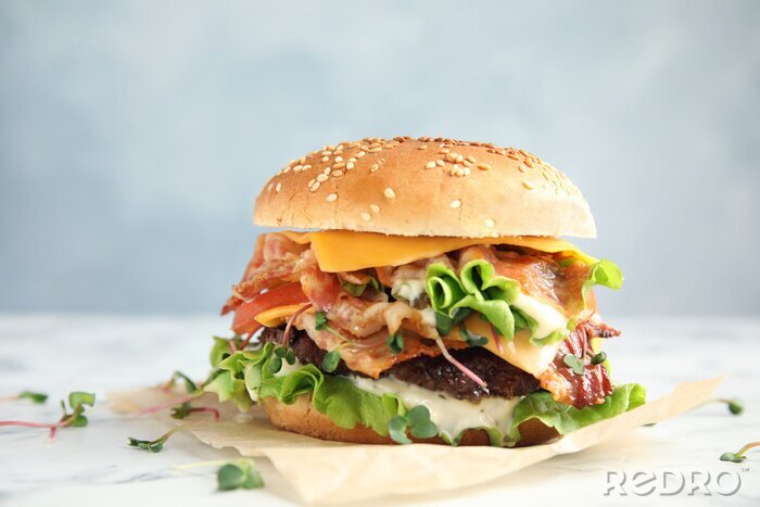 Fotobehang Tasty burger with bacon on table against color background