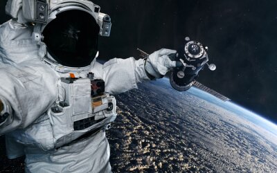 The astronaut holds in his hand a space station in orbit of the Earth. Solar system. Science fiction. Elements of this image furnished by NASA