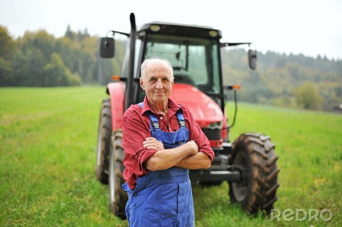 Fotobehang Trotse boer staat voor zijn rode tractor