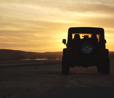voertuig in de woestijn bij zonsondergang