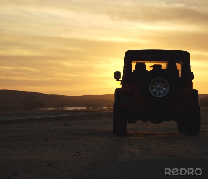 Fotobehang voertuig in de woestijn bij zonsondergang