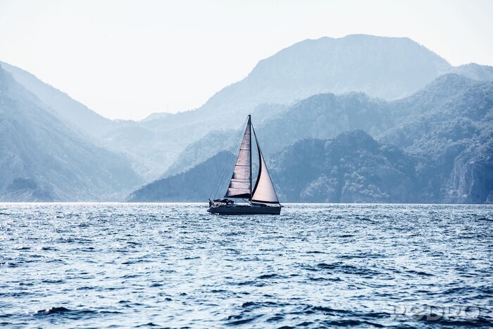 Fotobehang Zeilboot en bergachtig eiland