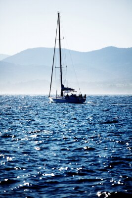 Fotobehang Zeilboot met op de achtergrond land
